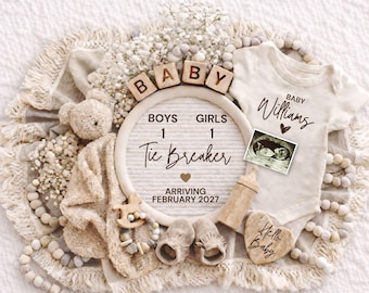 May include: A neutral-toned baby announcement with a teddy bear, baby clothes, and a letter board that reads "Tie Breaker" with the arrival date of February 2027. Includes baby shoes, a wooden toy, and a sonogram.