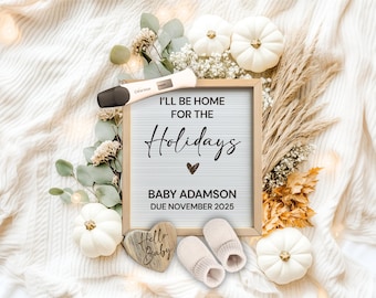 May include: A pregnancy announcement with a white letter board that reads "I'll be home for the holidays" with a heart and "Baby Adamson due November 2025". The letter board is surrounded by white pumpkins, greenery, and a wooden sign that reads "Hello Baby".