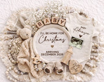 May include: A neutral-toned baby announcement with a cream-colored onesie, ultrasound image, and wooden accents. The announcement includes the text "I'll be home for Christmas" and "Arriving December 2026". A teddy bear and baby shoes are also present.