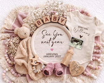 May include: A baby announcement with a cream-colored onesie, ultrasound image, and wooden blocks spelling "BABY." The announcement includes the text "See You next year" and "Arriving January 2027."