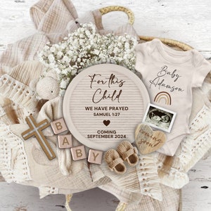 Può includere: Un cartello di legno con il testo "For this Child We Have Prayed Samuel 1:27 Coming September 2024" circondato da articoli per bambini, tra cui un body, scarpine, una croce e blocchi che compongono la parola "Baby".