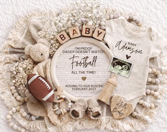 May include: A neutral-toned baby announcement with a football, teddy bear, and baby shoes. The announcement includes the text "I'm proof Daddy doesn't watch Football all the time!" and "Adding to our roster February 2027."