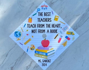 May include: A white graduation cap with a blue, yellow, and red school-themed design. The text on the cap reads "The Best Teachers Teach From The Heart, Not From A Book." The cap also includes the text "B.A. Education, Florida State University, Ms. Sanchez, 2024."