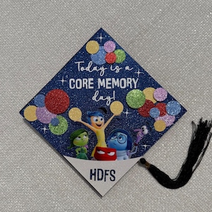 Könnte beinhalten: Eine marineblaue, glitzernde Abschlusskappe mit dem Text "Today is a CORE MEMORY day!" und Figuren aus dem Film Alles steht Kopf. Bunte Glitzerkreise und die Initialen "HDFS" sind ebenfalls abgebildet.