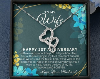 May include: A silver necklace with two intertwined hearts, presented in a black gift box with a message that reads "To My Wife Happy 1st Anniversary. Mere words cannot begin to tell you how I feel. You're the one thing in my life I can count on to be real. We've stood the test of time, we've walked the narrow road. And at the end of every day it's you I want to hold. You are the love of my life. My Always and Forever. Love, Your Husband."