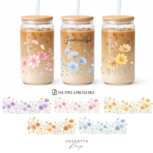Puede incluir: Tres vasos de vidrio con tapas y pajitas de madera, llenos de una bebida. Cada vaso está decorado con diseños florales en rosa, azul y amarillo. Un vaso tiene el nombre "Samantha". La imagen también muestra diseños de bordes florales.