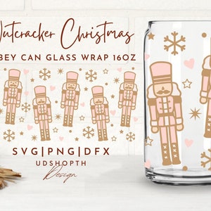 Könnte beinhalten: Eine transparente Libbey-Glasverpackung mit einem rosa-goldenen Nussknacker-Weihnachtsdesign. Das Design umfasst Nussknacker-Figuren, Schneeflocken, Herzen und Sterne. Das Glas hat 473 ml.