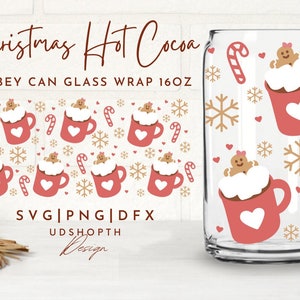 May include: Clear glass Libbey can wrap with a Christmas Hot Cocoa design. The design features red mugs with white whipped cream, gingerbread people, candy canes, snowflakes, and hearts. The text "Christmas Hot Cocoa" is at the top.