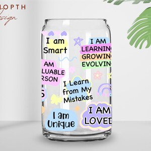 May include: A clear glass can with colorful stickers featuring positive affirmations like "I am Smart", "I am Unique", and "I am Loved".