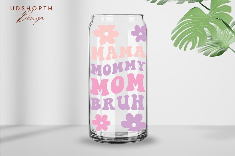 Puede incluir: Una lata de vidrio transparente con un dise&ntilde;o rosa y morado. La lata tiene las palabras "Mama", "Mommy", "Mom" y "Bruh" escritas en una fuente retro. Tambi&eacute;n hay flores rosas y moradas en la lata.