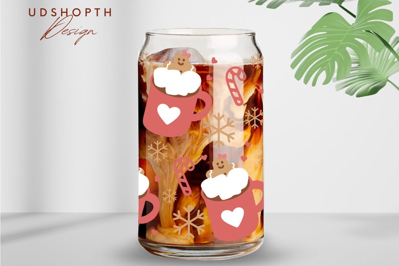 May include: A clear glass can-shaped cup filled with a beverage, featuring a festive design. The design includes pink mugs with white hearts, gingerbread men, snowflakes, and candy canes. The text "UDSHOPTH Design" is at the top left.