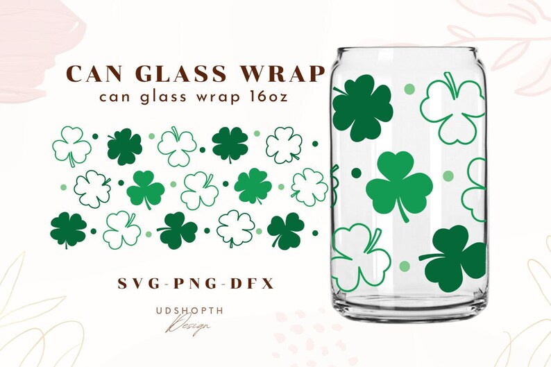 Op de afbeelding: Een transparante glazen can-wrap met een groen klaverbladpatroon. De wrap is ontworpen voor een 473 ml blik. De tekst "CAN GLASS WRAP" en "can glass wrap 16oz" staat op de afbeelding. De tekst "SVG - PNG - DFX" en "UDSHOPTH Design" staat ook op de afbeelding.