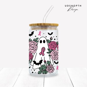 May include: A clear glass tumbler with a bamboo lid and a pink ribbon design. The tumbler features a ghost with a pink ribbon, surrounded by pink roses and bats. The text "UDSHOPTH Design" is visible in the top right corner of the image.