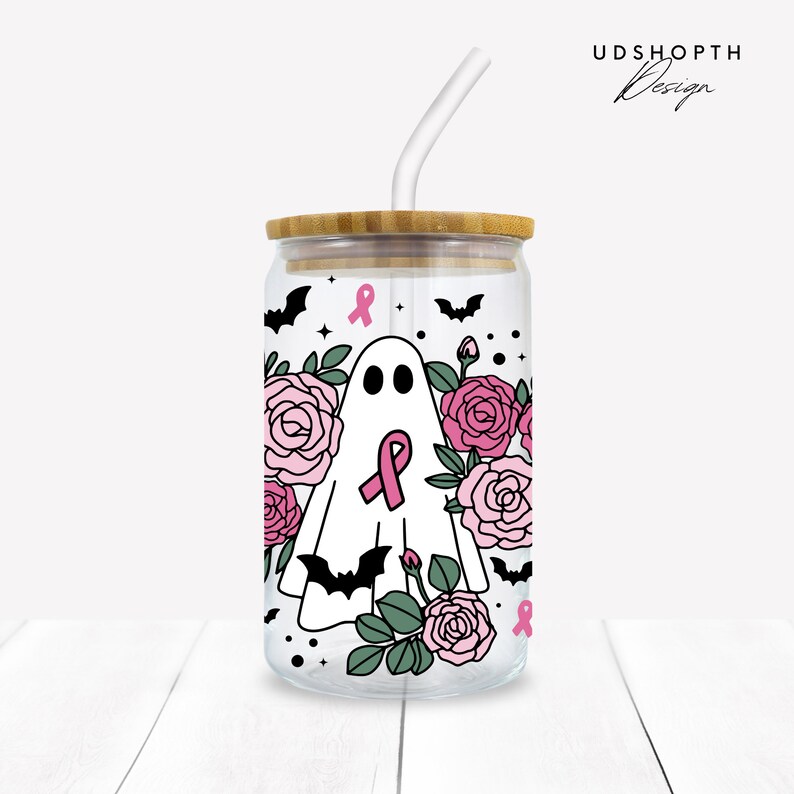 May include: A clear glass tumbler with a bamboo lid and a pink ribbon design. The tumbler features a ghost with a pink ribbon, surrounded by pink roses and bats. The text "UDSHOPTH Design" is visible in the top right corner of the image.