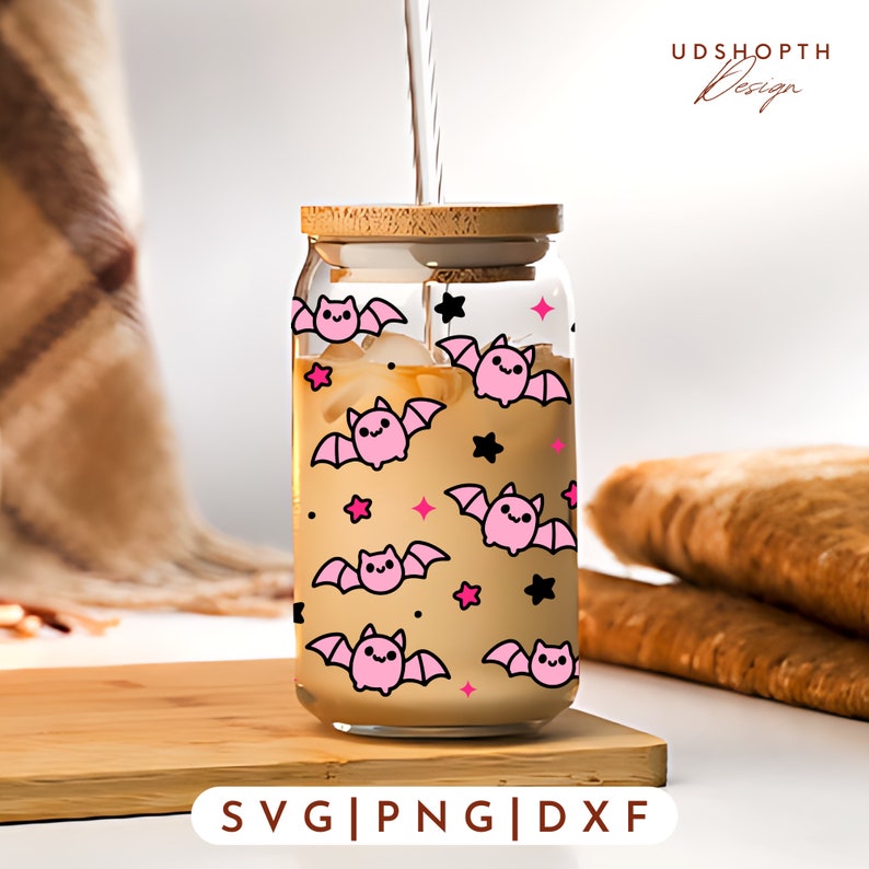 May include: A clear glass tumbler with a bamboo lid features a repeating pattern of pink bats and black stars. The tumbler is filled with a light brown liquid.