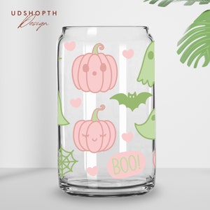以下が含まれることがあります： ピンクとグリーンのハロウィーンデザインが施された透明なガラス製の缶。缶には、カボチャ、コウモリ、幽霊、ハート、クモの巣が描かれています。缶には「BOO！」の文字が印刷されています。