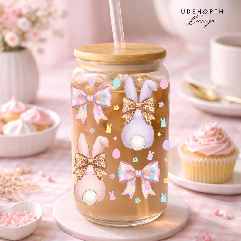 May include: A clear glass tumbler with a wooden lid and straw, decorated with Easter bunny designs and bows. The tumbler is filled with a brown liquid. The design includes the text "UDSHOPTH Design".