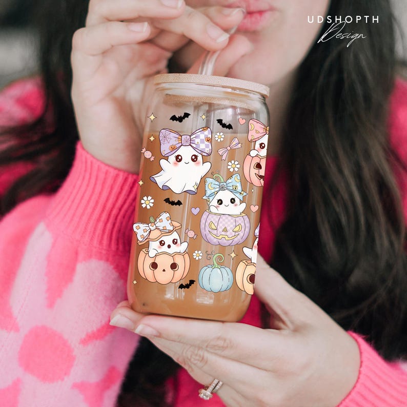 May include: A clear glass tumbler with a bamboo lid, decorated with Halloween-themed illustrations. The design includes cute ghosts, pumpkins, bats, and bows in pastel colors. The tumbler has a straw and the text "UDSHOPTH Design".