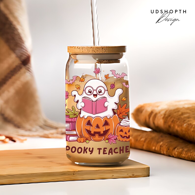 Pu&ograve; includere: Un barattolo di vetro con un coperchio di legno e un design a tema Halloween. Il barattolo presenta un fantasma dei cartoni animati che legge un libro, zucche e il testo "Spooky Teacher".