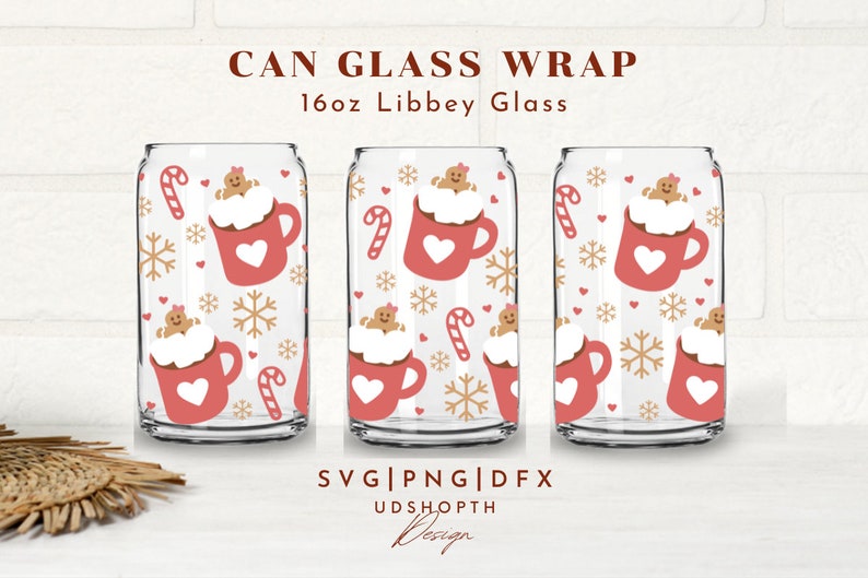 May include: Three clear can glasses with a festive design. Each glass features a repeating pattern of a red mug with a heart, gingerbread person, candy cane, and snowflakes. The text "CAN GLASS WRAP" and "16oz Libbey Glass" is at the top.
