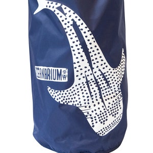 Pode incluir: Uma bolsa seca azul marinho com um design de tubarão-baleia branco e o texto "Oceanarium" impresso no lado.