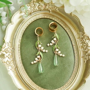 Puede incluir: Un letrero de madera hecho a mano con la palabra "Welcome" en un estilo manuscrito. El letrero está pintado de blanco con un acabado envejecido, y una pequeña hoja verde está adjunta. Diseñado para uso en interiores o exteriores.