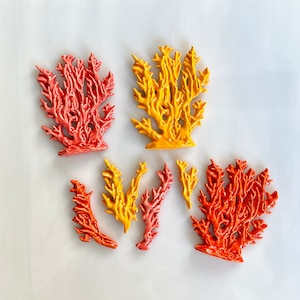 May include: A collection of coral-shaped decorative objects in various shades of red, orange, and yellow. The objects have a textured surface and are arranged on a white background. These decorative pieces are ideal for coastal or nautical-themed decor.