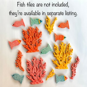 May include: Ceramic coral and fish tiles in shades of orange, yellow, and teal. The fish have orange and blue accents. The text in the image reads: "Fish tiles are not included, they're available in separate listing."