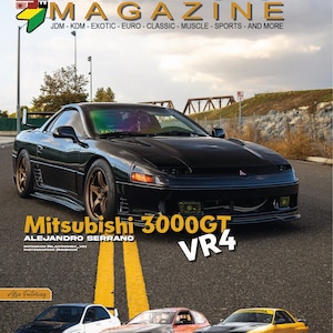 May include: A black Mitsubishi 3000GT VR4 car with gold wheels, a yellow license plate, and yellow fog lights. The car is parked on a paved road with yellow lines. The car is featured in StanceAuto Magazine.