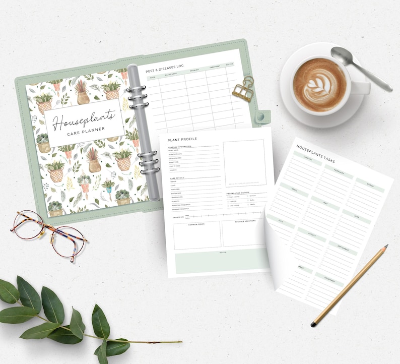 Peut inclure: Un planificateur de soins pour plantes d'int&eacute;rieur avec un classeur vert clair, ouvert pour r&eacute;v&eacute;ler des pages lign&eacute;es. La couverture pr&eacute;sente un motif aquarelle de plantes en pot. Une tasse de caf&eacute;, des lunettes et un crayon sont &eacute;galement sur la table.