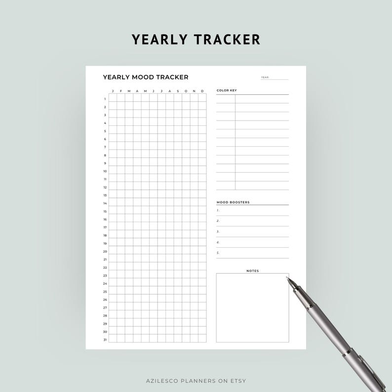 May include: A white Yearly Mood Tracker planner with a grid for daily entries, color key, mood boosters, and notes sections. The text "YEARLY TRACKER" is at the top. A silver pen rests on the bottom right corner. The Etsy shop name "AZILESCO PLANNERS ON ETSY" is at the bottom.