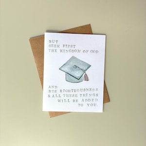May include: A graduation greeting card with a watercolor illustration of a mortarboard and tassel. The card is white with black text that reads "But seek first the kingdom of God and his righteousness & all these things will be added to you." The card is on a brown envelope.