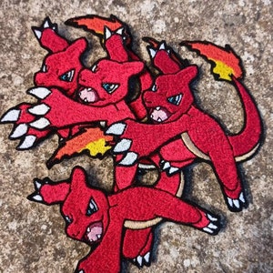 May include: Five red and white embroidered patches of a cartoon fire-breathing dragon. The patches are layered on top of each other.