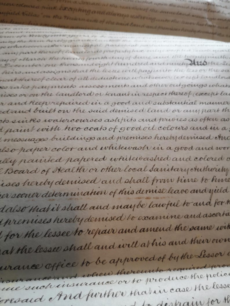 May include: Close-up of an antique document featuring handwritten cursive script. The aged paper has a cream hue, and the ink is dark brown. The text appears to be legal or historical, with visible words and phrases.