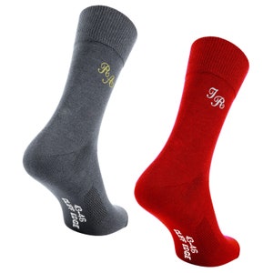May include: A pair of socks, one gray and one red, with embroidered initials. The socks have a breathable mesh panel and the text "43-46 CLIFF EDGE" on the bottom.
