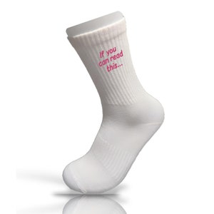 Könnte beinhalten: Weiße Socken mit pinkfarbenem Sticktext, der "Wenn du das lesen kannst..." lautet.