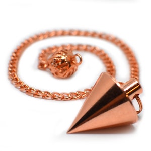 May include: A copper-colored pendulum with a pointed tip and a chain attached to a small, decorative ball. The pendulum is used for divination and dowsing.