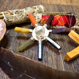 Pu&ograve; includere: Una stella chakra di cristallo a sette punte con un cristallo di quarzo chiaro al centro. Le punte della stella sono fatte di cristalli di diversi colori, tra cui rosso, arancione, giallo, verde, blu, indaco e viola. La stella &egrave; circondata da mazzi di salvia, bastoncini di palo santo e petali di fiori secchi.