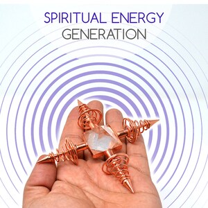 May include: A copper orgonite pyramid with a clear quartz crystal in the center and four copper coils with pointed ends. The orgonite is in a hand, and the background is a purple and white concentric circle pattern. The text "SPIRITUAL ENERGY GENERATION" is at the top of the image.