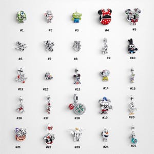 May include: A collection of twenty-five silver-toned metal charms featuring various cartoon characters and symbols, each labelled with a number from 1 to 25. The charms include colourful enamel details, sparkling stones, and intricate designs.
