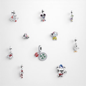 May include: A collection of ten silver charms featuring various designs including a ladybird with a four-leaf clover, a wizard mouse, a mouse with a bow, a dwarf, and other character-themed figures with colourful enamel and crystal accents.