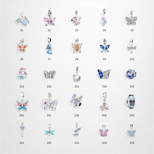 Könnte beinhalten: Eine Sammlung von silberfarbenen Charm-Anhängern mit Schmetterlings-, Libellen- und Blumendesigns. Die Charms sind mit farbigem Emaille und funkelnden Kristallen verziert. Jeder Charm ist mit einem "Z" und einer Nummer versehen.
