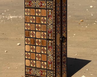 Peut inclure: Un coffret en bois rectangulaire et haut, orné d'incrustations géométriques complexes dans des tons de marron, de rouge et de noir. Le coffret a une porte à charnière avec un fermoir en métal et une bordure sombre.