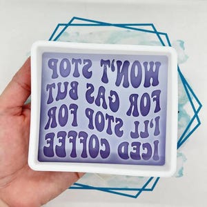 May include: A square, white resin mould with the text "I'll Stop For Iced Coffee But Won't Stop For Gas". The text is in a purple, retro font. The mould is held in a hand, with a blue and white geometric design in the background.