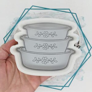 May include: A set of three ceramic mugs with a speckled, matte finish. The mugs are in shades of cream, light gray, and dark gray. Each mug has a simple, minimalist design, perfect for coffee or tea.