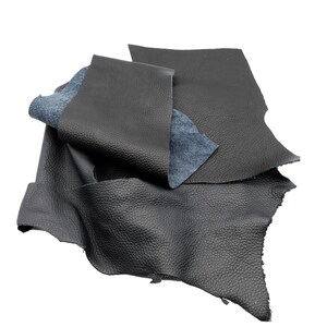 Könnte beinhalten: Ein Stapel schwarzer Lederreste, einige mit blauer Rückseite, für Bastelprojekte.