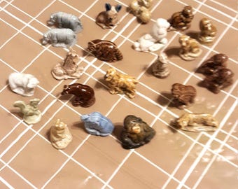 May include: A collection of 20 small ceramic animal figurines. The figurines are painted in various colors, including brown, white, blue, and black. The figurines are arranged on a brown and white checkered surface.