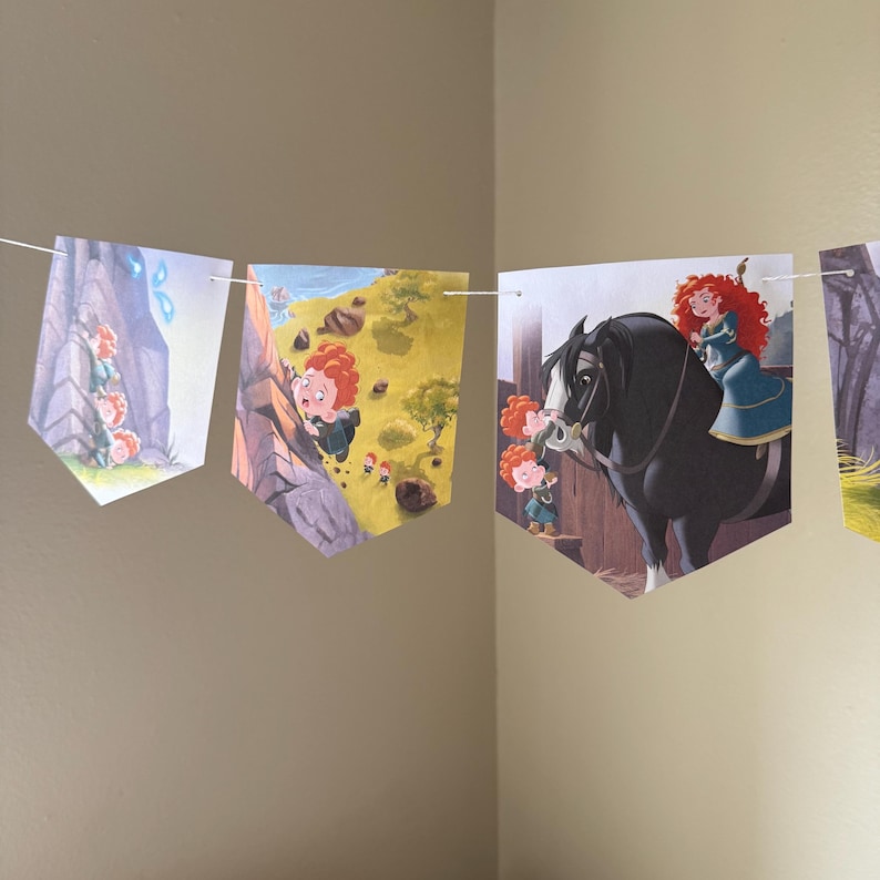 Peut inclure: Une guirlande de fanions illustr&eacute;s tir&eacute;s d'un film pour enfants. Les fanions sont reli&eacute;s par une ficelle blanche. Les illustrations repr&eacute;sentent une jeune fille rousse dans diverses sc&egrave;nes, notamment en train d'escalader une falaise et de monter un cheval noir.