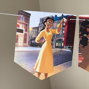 以下が含まれることがあります： 街を背景に、黄色のドレスを着た女性の漫画イラストが描かれたペナントバナー。 女性は紙を持っています。 バナーは白い紐でつながれています。