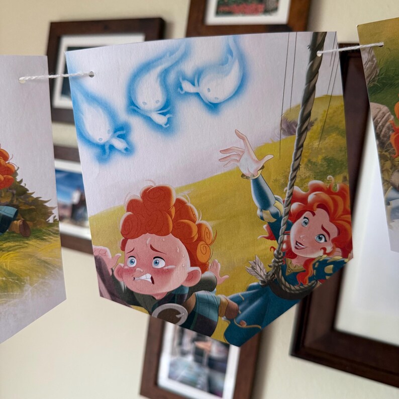 Peut inclure: Une banni&egrave;re avec une illustration color&eacute;e de deux personnages aux cheveux boucl&eacute;s roux, l'un effray&eacute; et l'autre souriant. Au-dessus, trois figures bleues en forme de fant&ocirc;mes. La banni&egrave;re est suspendue &agrave; une ficelle blanche.